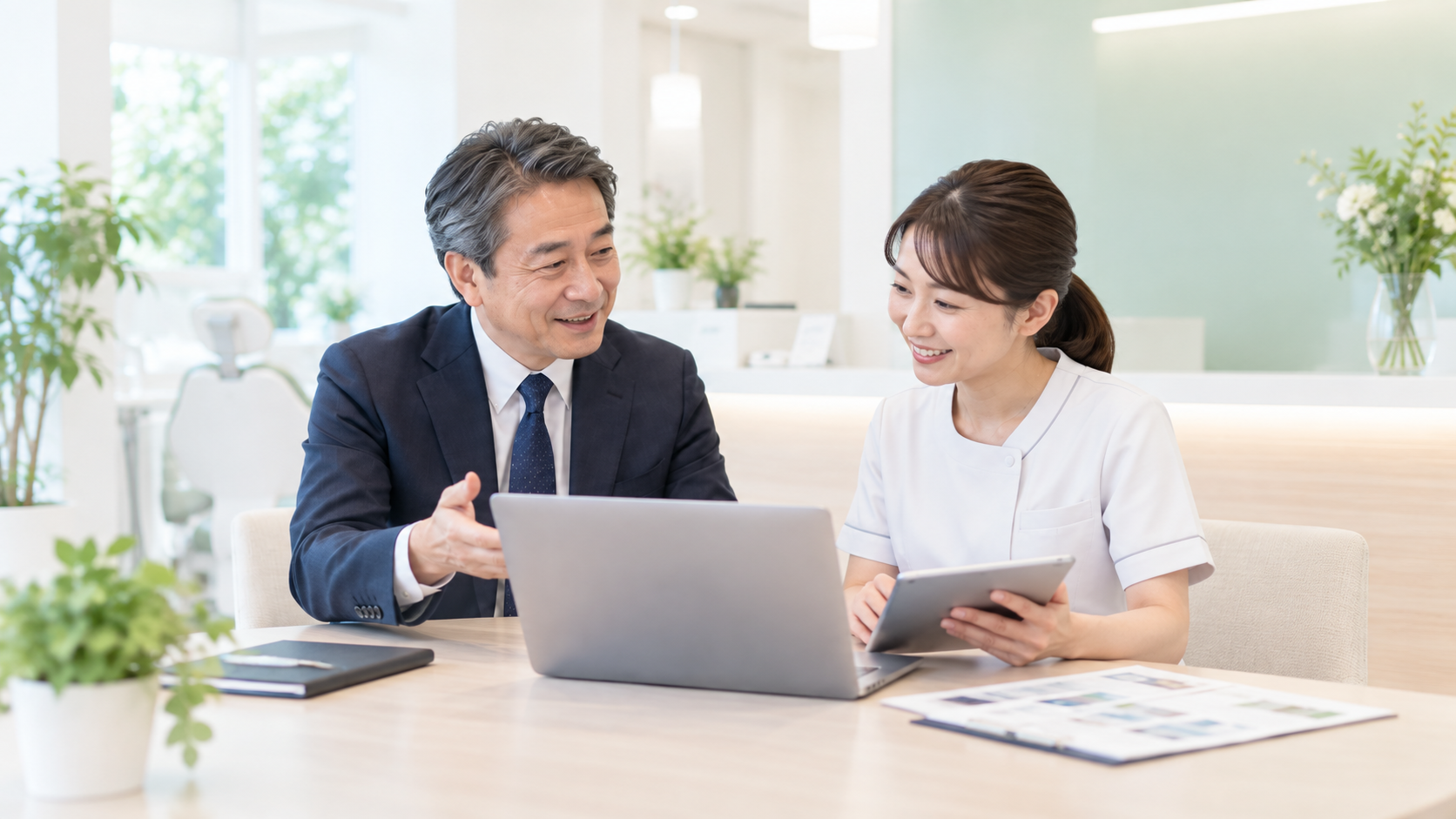 歯科医院のスタッフとパソコンや資料を見ながら打ち合わせをしている様子